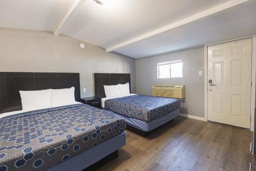 una camera d'albergo con due letti e una porta di Sands Inn by OYO Winnie a Winnie