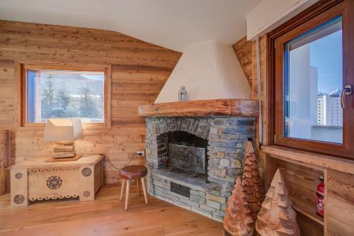 a living room with a stone fireplace in a log cabin at Danda Terrace Apartment - Happy Rentals in Sauze d'Oulx