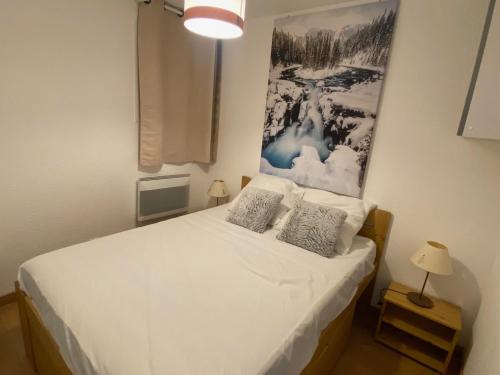 a bedroom with a white bed with a picture on the wall at Appartement Montgenèvre, 2 pièces, 5 personnes - FR-1-445-157 in Montgenèvre