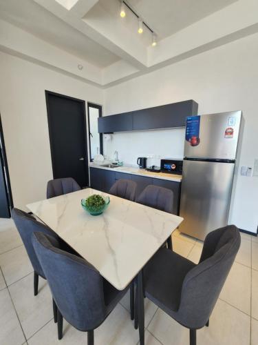 a kitchen with a table and chairs and a refrigerator at Executive Premium Urban Suites - Jelutong in Jelutong