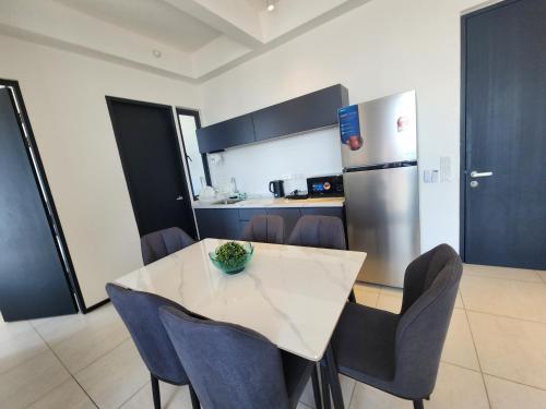 a kitchen with a table with chairs and a refrigerator at Executive Premium Urban Suites - Jelutong in Jelutong