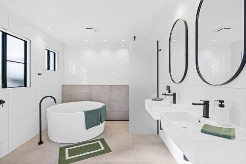 Un baño blanco con dos lavabos y una bañera. en Spearmint House - Art Deco Gem in Misty Mountains, en Berner Creek