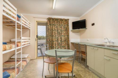 a room with a table and a kitchen with bunk beds at Injune Motel in Injune