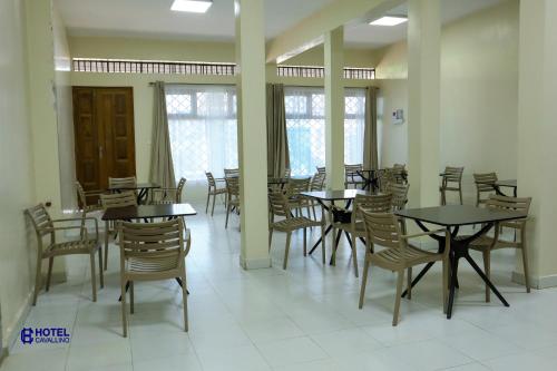 a dining room with tables and chairs and windows at Hotel Cavallino in Kakamega