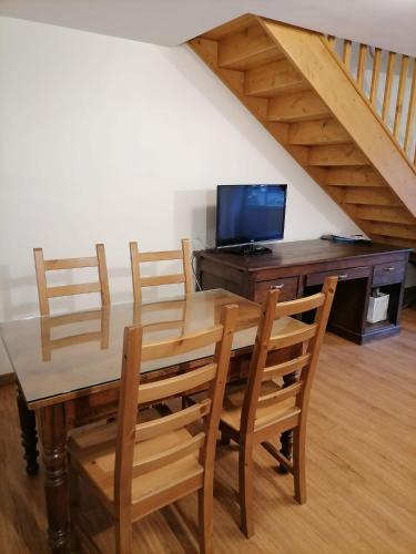 a dining room table with chairs and a desk with a television at Le Relais de Garabit in Anglards-de-Saint-Flour