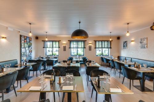 ein Restaurant mit Tischen, Stühlen und Fenstern in der Unterkunft Hotel Italia in Zelzate