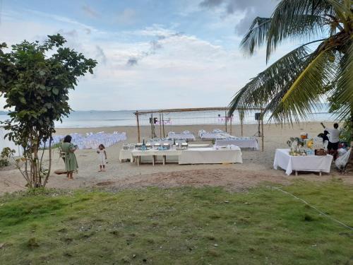 una recepción de bodas en la playa con mesas blancas en CRUISER'S BEACH RESORT, en San Agustin