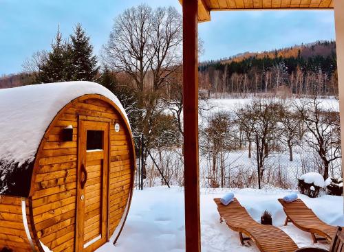 een blokhut in de sneeuw met twee stoelen bij Apartmány U Rodinky in Lipova Lazne