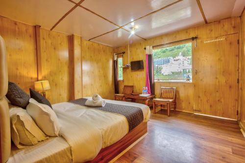 a bedroom with a bed in a room with wooden walls at The Shivalaya Retreat - A River Side Resort in Jagatsukh