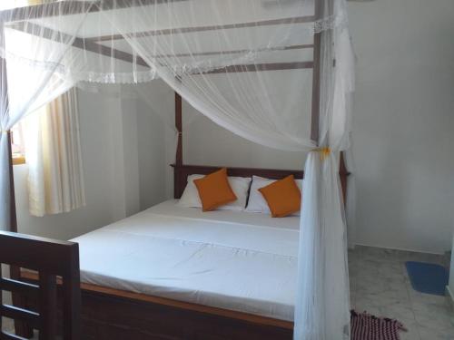 a bedroom with a canopy bed with orange pillows at Friendly house in Galle