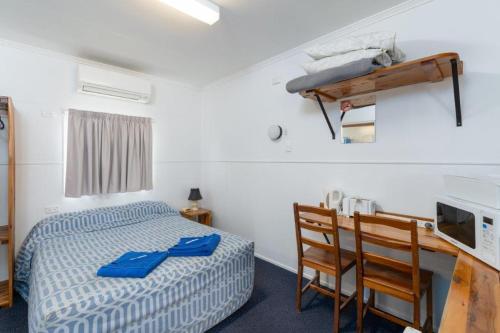 - une chambre avec un lit, une table et des chaises dans l'établissement Injune Motel, à Injune