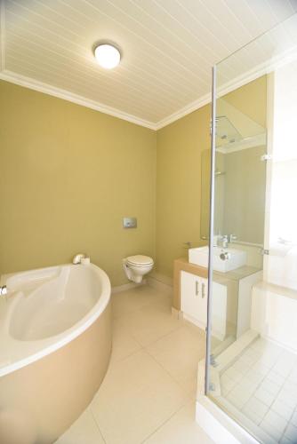 a bathroom with a tub and a toilet and a sink at Bayview in Gordonʼs Bay