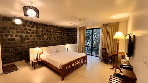 a bedroom with a bed and a brick wall at Mango Hill Yercaud in Yercaud