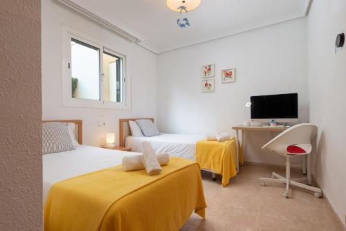 a bedroom with two beds and a desk and a tv at Es Mirador - Cales de Mallorca in Calas de Mallorca