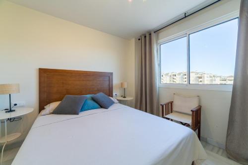 um quarto com uma cama branca e uma grande janela em Agua Serena em Roquetas de Mar