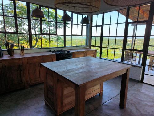a kitchen with a wooden table in front of windows at Eloff Guest House and Gallery in White River