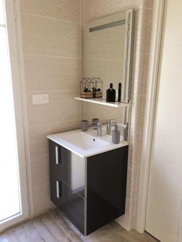 une salle de bain avec un lavabo et un miroir dans l'établissement La Cigale du Pyla, au cœur de l'écoquartier avec piscine commune, à La Teste-de-Buch