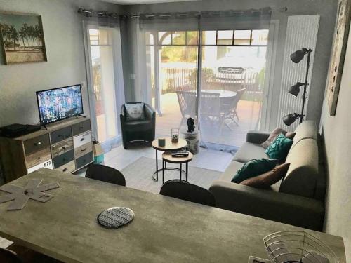 een woonkamer met een bank en een tafel bij La Cigale du Pyla, au cœur de l'écoquartier avec piscine commune in La Teste-de-Buch