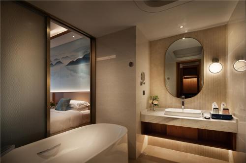 a bathroom with a tub and a sink and a mirror at Arcadia Resort Hainan in Lingshui