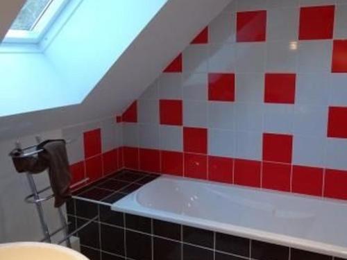 y baño de azulejos rojos y blancos con bañera. en Gîte La Bazoge, 5 pièces, 7 personnes - FR-1-410-254, en La Bazoge