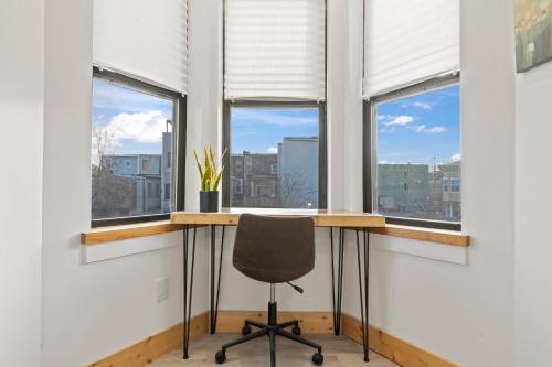 un bureau avec un bureau et une chaise en face des fenêtres dans l'établissement Goodseed Suites Philadephia Center, à Philadelphie