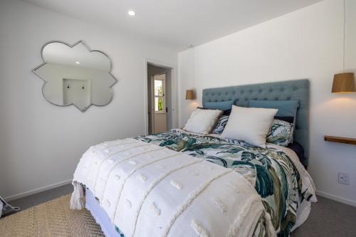 a bedroom with a bed with a blue headboard at Coco Grove Oneroa - Luxe Escape with Spa Pool in Blackpool