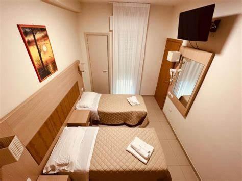 a small hotel room with two beds and a mirror at Hotel Cuba Aeroport Restaurant in Rimini