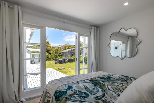 a bedroom with a bed and a large window at Coco Grove Oneroa - Luxe Escape with Spa Pool in Blackpool