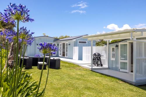 a row of modular homes in a yard with purple flowers at Coco Grove Oneroa - Luxe Escape with Spa Pool in Blackpool