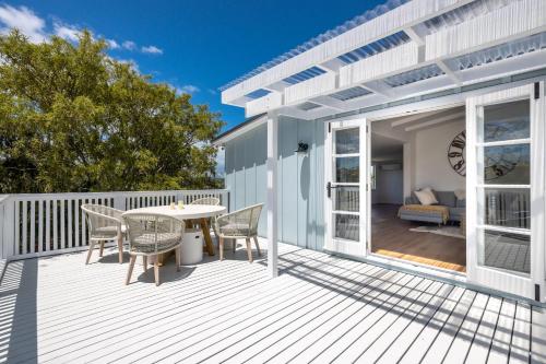 a patio with a table and chairs on a deck at Coco Grove Oneroa - Luxe Escape with Spa Pool in Blackpool