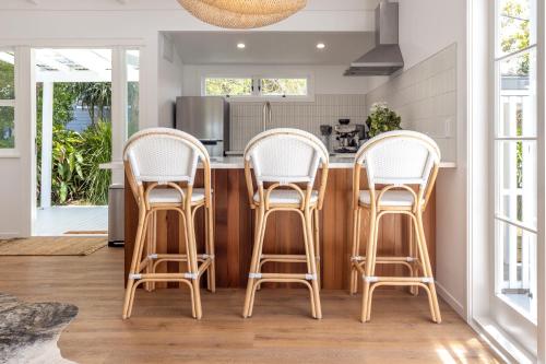 a kitchen with four chairs around a kitchen island at Coco Grove Oneroa - Luxe Escape with Spa Pool in Blackpool
