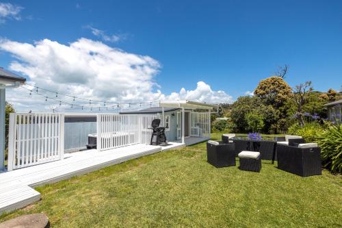 a backyard with a white fence and some grass at Coco Grove Oneroa - Luxe Escape with Spa Pool in Blackpool