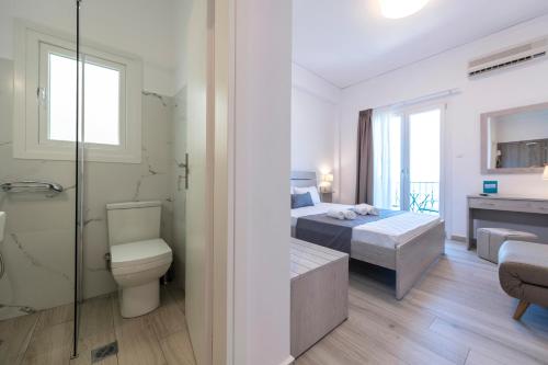 a bathroom with two beds a toilet and a shower at Paraskevas Boutique Hotel in Tiros
