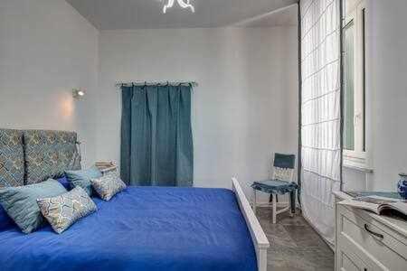 Un dormitorio con una cama azul y una ventana en Sorrento Capo Apartments by Gocce en Sorrento