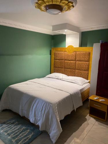 een slaapkamer met een groot bed en een groene muur bij Primier Mansion Guest Home in Limbe