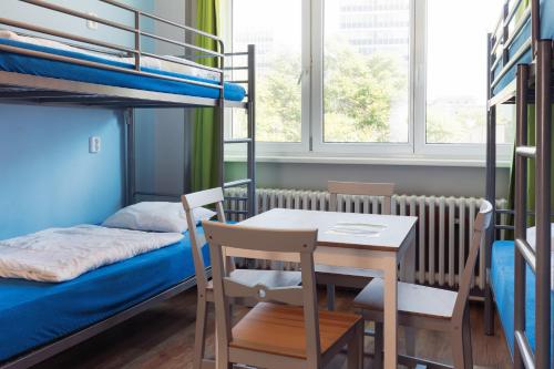 Patio Hostel Dorms في براتيسلافا: غرفة مع طاولة وسرير بطابقين