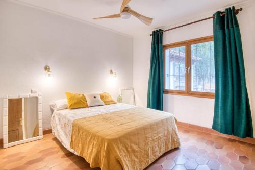 Un dormitorio con una cama con cortinas verdes y una ventana. en Mas Tomasi 264, en Pals