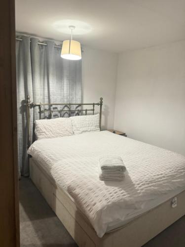 a bedroom with a bed with white sheets and a lamp at Master room in Bristol