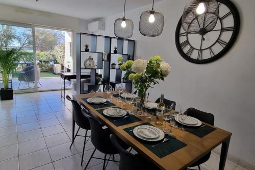 a dining room table with chairs and a clock on the wall at Superbe Appartement déco, Sur la plage, vue mer, 2 chambres, refait à neuf, Climatisé, Parking privé, Piscine in Sète