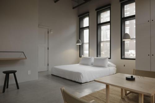 a bedroom with a bed and a table and windows at kodō hotel in Los Angeles