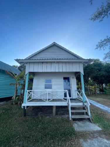 a small white house with a porch and stairs at Sandy Beach Bungalows By EHM in Koh Rong Sanloem
