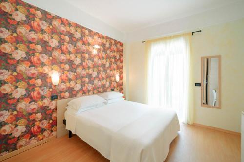 リミニにあるHotel Villa Marinaの花の壁のベッドルーム(白いベッド1台付)