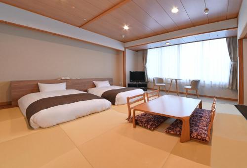 a hotel room with two beds and a table at 朝里川温泉ホテル in Otaru