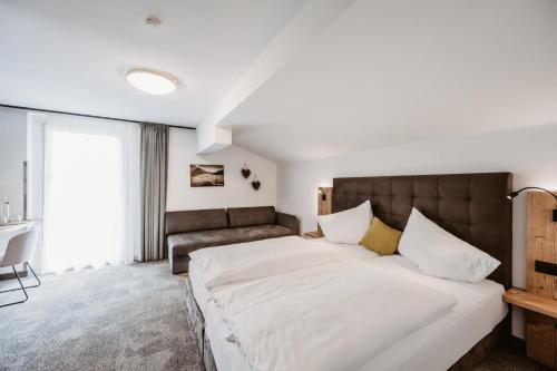 a bedroom with a large bed and a couch at Landhotel Laudersbach in Altenmarkt im Pongau