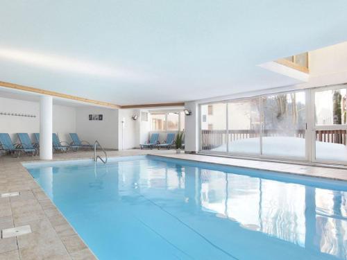 une grande piscine avec de l'eau bleue dans un immeuble dans l'établissement Duplex 4 chambres avec piscine et parking au centre du village - 10 pers - FR-1-505-122, à Notre-Dame-de-Bellecombe