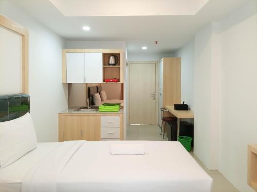 um quarto com uma cama branca e uma secretária em Brand New Studio at De Prima Apartment Medan By Travelio em Medan