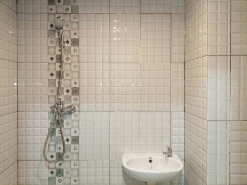 uma casa de banho em azulejos brancos com um lavatório e um chuveiro em Brand New Studio at De Prima Apartment Medan By Travelio em Medan