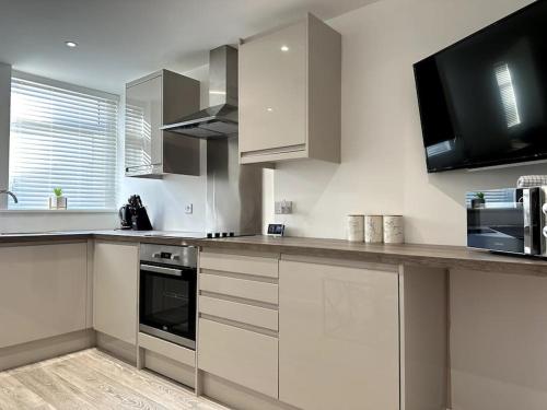 eine Küche mit weißen Schränken und einer Arbeitsplatte in der Unterkunft Cosy 1 Bedroom Apartment In Cardiff in Cardiff