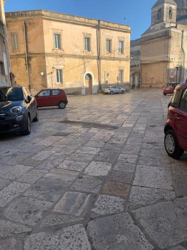 a stone parking lot with cars parked in front of a building at My Family Home in Francavilla Fontana