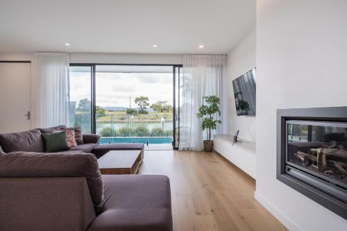 a living room with a couch and a fireplace at Sunset Marina - An Architectural Gem by the Beach in Safety Beach